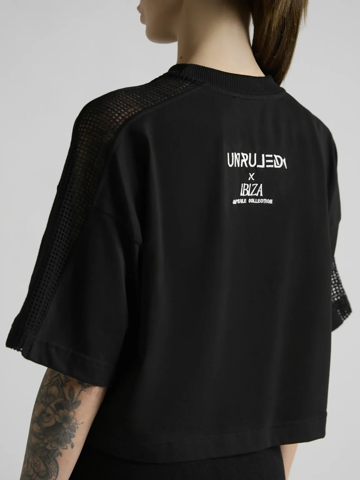 Women's black crop top with mesh inserts on shoulders and sides by UNRULED IBIZA collection.