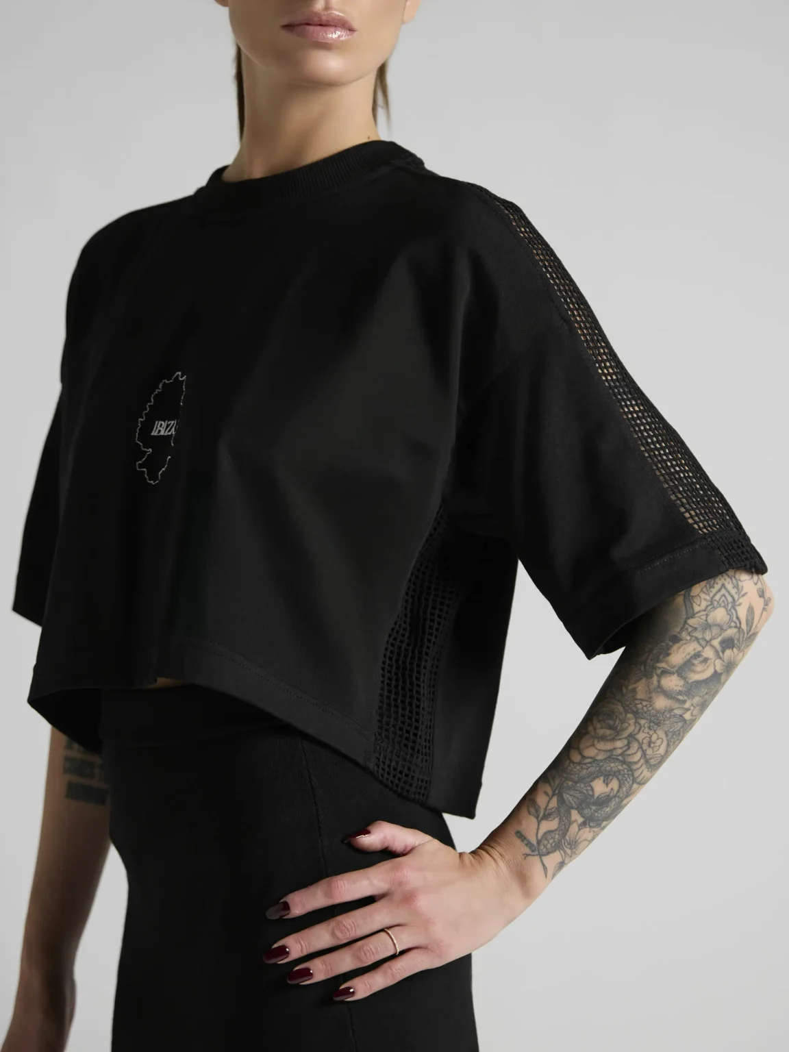 Women's black crop top with mesh inserts on shoulders and sides by UNRULED IBIZA collection.